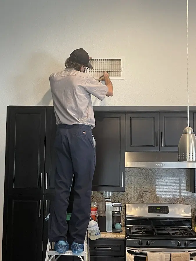 Technician inspecting an air vent during HVAC service in Sunset